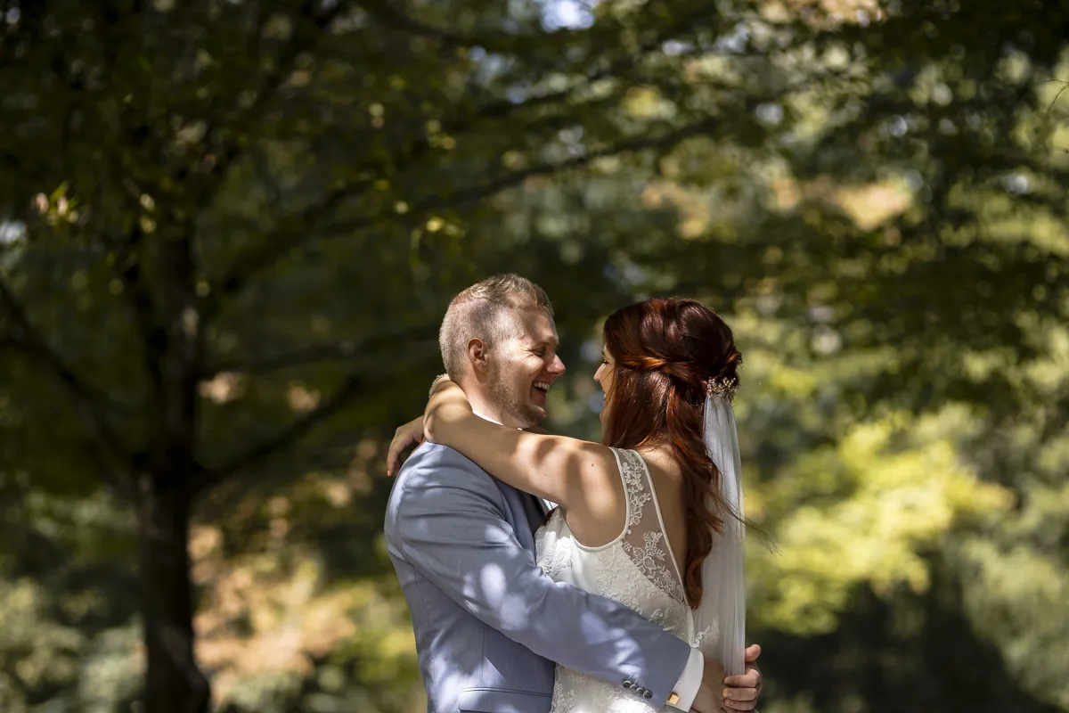 Brautpaar im Park umarmt sich und lacht sich an